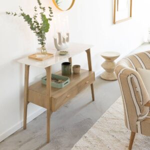 The Vandana Elara Stellar – Hari Console Table is a refined expression of contemporary elegance, designed to elevate modern interiors with a perfect balance of luxury and functionality. Crafted from solid mango wood and crowned with a premium white marble top, this console table brings together natural warmth and timeless sophistication in one harmonious design. The smooth marble surface instantly enhances the console’s visual appeal, offering a clean and luminous contrast to the rich texture and grain of mango wood. Accentuated by two spacious drawers with gold-tone metal handles, the Hari console introduces a subtle touch of luxury while maintaining a minimalist and contemporary aesthetic. The metallic detailing adds refinement without overpowering the natural materials, making it an ideal fit for both modern and transitional interiors. With dimensions of 83 cm height, 100 cm width, and 40 cm depth, this console provides generous surface space while retaining a slim, space-efficient profile. It is perfectly suited for entryways, hallways, living rooms, bedrooms, or upscale commercial spaces, where elegance and storage are equally important. The marble top offers an ideal platform for decorative accents, mirrors, lamps, or art pieces, while the integrated drawers allow discreet storage for keys, documents, or everyday essentials. Constructed from solid mango wood, the console ensures durability, strength, and long-lasting performance. Mango wood is prized for its sustainability and resistance, making this piece suitable for both residential and hospitality interiors. The console is delivered fully assembled, allowing for immediate placement and use without installation effort. Each marble top is naturally unique, showcasing individual veining patterns and mineral variations that make every piece one of a kind. These natural characteristics enhance the authenticity and premium appeal of the console, ensuring exclusivity in every unit. The Vandana Elara Stellar console seamlessly complements contemporary, modern luxury, Scandinavian, and boutique-style interiors. Whether styled as a statement piece in an entryway or as a functional accent in a living space, the Hari console table delivers timeless beauty, practical storage, and elevated design—making it a valuable addition to any curated interior setting.