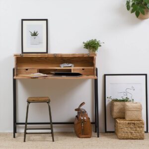 Vandana Lyra Lunaris – Milo Industrial Secretary Desk in Dark Acacia Wood & Metal Reimagine classic functionality with a modern industrial twist through the Vandana Lyra Lunaris Milo Secretary Desk, a refined fusion of solid dark acacia wood and durable metal. Inspired by the timeless secretary desk, this versatile piece retains its signature opaque, fold-down design while introducing contemporary materials and clean industrial lines. Crafted with a solid acacia wood work surface and a robust metal base, the Milo secretary desk offers exceptional strength, stability, and long-term durability. The rich dark acacia tones highlight natural wood grain patterns, adding warmth and depth that beautifully contrast with the sleek metal structure. This balanced combination makes the desk suitable for industrial, modern, and urban interiors alike. Designed to support both productivity and organization, the Milo desk features two practical drawers and two open shelves, providing generous storage for stationery, documents, accessories, or everyday essentials. The intelligent layout helps keep your workspace neat and efficient, allowing you to focus without clutter. When work is done, the desk can be folded down, instantly transforming into an elegant console table—perfect for maintaining a clean, stylish interior. With compact yet functional dimensions of 100 cm width, 30 cm depth, and 84 cm height, this secretary desk fits effortlessly into home offices, bedrooms, living rooms, or study areas. Its space-saving design makes it an ideal solution for modern homes where flexibility and smart furniture are essential. Delivered fully assembled with screw-in feet, the Vandana Lyra Lunaris Milo Secretary Desk is ready for immediate use. Whether styled as a dedicated workspace or a decorative console, this piece offers a seamless blend of design, practicality, and timeless appeal—making it a standout addition to both residential and boutique commercial interiors.