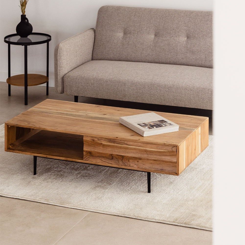 Vandana Grand Elara Petter Rectangular Acacia Wood Coffee Table (120 × 60 cm) is a sophisticated combination of contemporary design, premium materials, and everyday functionality. Designed to complement modern interiors, this elegant coffee table adds character, organization, and timeless appeal to your living space. Expertly crafted from solid acacia wood, the tabletop showcases the natural richness of the wood grain, offering excellent durability and resistance to daily use. Acacia wood is widely appreciated for its strength and long lifespan, making it an ideal choice for high-quality living room furniture. The warm wooden surface brings a natural and welcoming atmosphere while maintaining a refined, modern look. Supporting the tabletop are sturdy iron legs, which add a subtle industrial touch while ensuring maximum stability and structural strength. This contrast between natural wood and metal creates a balanced and versatile design that fits effortlessly into contemporary, industrial, modern rustic, and transitional interiors. A standout feature of the Vandana Grand Elara Coffee Table is its spacious integrated drawer, thoughtfully designed to keep everyday essentials neatly stored and easily accessible. It provides ample space for remote controls, magazines, books, coasters, or small accessories, helping maintain a clean and clutter-free living room environment without sacrificing style. The rectangular 120 × 60 cm format offers a generous surface area, making the table ideal for serving coffee and snacks, entertaining guests, or displaying decorative elements such as trays, vases, candles, or books. Its well-proportioned height ensures comfortable use alongside sofas and seating arrangements. For long-lasting beauty, simple maintenance is recommended—cleaning with a damp cloth and avoiding harsh chemical products. As with all natural wood furniture, slight variations in color, grain pattern, and texture may occur. Differences may also appear due to lighting conditions or screen calibration. These variations are natural characteristics of solid wood and highlight the authenticity of handcrafted furniture. The Vandana Grand Elara Petter Acacia Wood Coffee Table is an ideal choice for buyers seeking premium craftsmanship, smart storage, and elegant design in a durable and stylish living room centerpiece. Vandana Grand Elara Petter Rectangular Acacia Wood Coffee Table (120 × 60 cm) is a sophisticated combination of contemporary design, premium materials, and everyday functionality. Designed to complement modern interiors, this elegant coffee table adds character, organization, and timeless appeal to your living space. Expertly crafted from solid acacia wood, the tabletop showcases the natural richness of the wood grain, offering excellent durability and resistance to daily use. Acacia wood is widely appreciated for its strength and long lifespan, making it an ideal choice for high-quality living room furniture. The warm wooden surface brings a natural and welcoming atmosphere while maintaining a refined, modern look. Supporting the tabletop are sturdy iron legs, which add a subtle industrial touch while ensuring maximum stability and structural strength. This contrast between natural wood and metal creates a balanced and versatile design that fits effortlessly into contemporary, industrial, modern rustic, and transitional interiors. A standout feature of the Vandana Grand Elara Coffee Table is its spacious integrated drawer, thoughtfully designed to keep everyday essentials neatly stored and easily accessible. It provides ample space for remote controls, magazines, books, coasters, or small accessories, helping maintain a clean and clutter-free living room environment without sacrificing style. The rectangular 120 × 60 cm format offers a generous surface area, making the table ideal for serving coffee and snacks, entertaining guests, or displaying decorative elements such as trays, vases, candles, or books. Its well-proportioned height ensures comfortable use alongside sofas and seating arrangements. For long-lasting beauty, simple maintenance is recommended—cleaning with a damp cloth and avoiding harsh chemical products. As with all natural wood furniture, slight variations in color, grain pattern, and texture may occur. Differences may also appear due to lighting conditions or screen calibration. These variations are natural characteristics of solid wood and highlight the authenticity of handcrafted furniture. The Vandana Grand Elara Petter Acacia Wood Coffee Table is an ideal choice for buyers seeking premium craftsmanship, smart storage, and elegant design in a durable and stylish living room centerpiece.