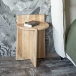 Vandana Crystal Flow Design Solid Acacia Wood Bedside Table – Trudy Collection The Vandana Crystal Flow bedside table from the Trudy collection is a refined interpretation of retro-inspired design, crafted to bring warmth, simplicity, and authenticity into contemporary interiors. Made entirely from solid acacia wood, this bedside table highlights the natural beauty of real wood through its smooth finish, rounded edges, and softly balanced proportions. Designed with clean lines and a compact footprint, this bedside table measures 40 cm in length, 31.5 cm in depth, and 60 cm in height, making it ideal for bedrooms where space efficiency and elegance go hand in hand. The solid acacia tabletop features a practical backsplash that subtly frames the surface, offering visual depth while helping protect the wall. The generous tabletop thickness of approximately 2.5 cm reinforces the durability and premium quality of the piece. The natural grain and warm tonal variations of acacia wood are enhanced by a protective varnish, preserving the wood’s organic character while ensuring resistance to everyday use. Rounded edges soften the overall silhouette, creating a welcoming and timeless aesthetic inspired by vintage furniture, yet perfectly suited to modern living. Supported by a robust central base with adjustable plastic glides, the Trudy bedside table offers excellent stability on various floor surfaces. Its solid structure reflects traditional craftsmanship, while the minimalist form allows it to integrate effortlessly into retro, Scandinavian, natural, or contemporary interiors. This bedside table is designed for versatility. It functions beautifully as a nightstand beside the bed, a compact side table in a living space, or a functional accent piece in boutique hospitality interiors. Its understated design allows it to complement a wide range of materials, from linen and wool textiles to metal or ceramic decorative accessories. Delivered in one package and easy to assemble, the Vandana Crystal Flow bedside table is a durable, elegant, and timeless furniture piece. It is ideal for customers seeking authentic solid wood furniture that combines simplicity, longevity, and refined design for everyday living.